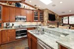 Kitchen has granite countertops, stainless steel appliances, and bar seating